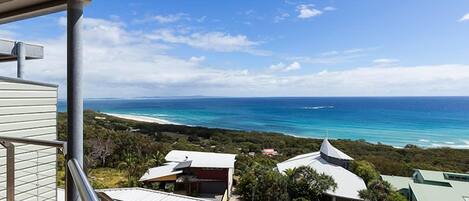 A coastal view from a balcony overlooking a beach and ocean.