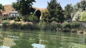 A serene pond with reflections of trees and a house in the background. - Amazing relaxing get-away home on the Snake River with river view and boat dock. (Hagerman)