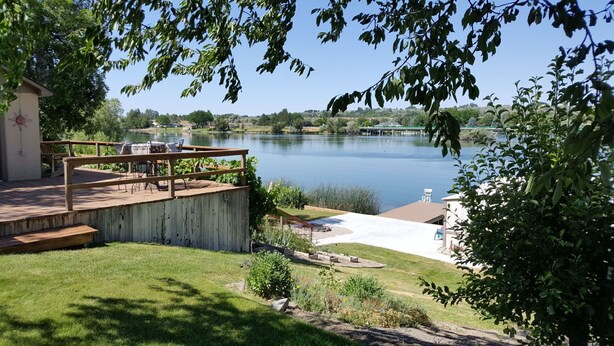 A lakeside deck with outdoor furniture, a small garden, and a view of the lake. - Amazing relaxing get-away home on the Snake River with river view and boat dock. (Hagerman)