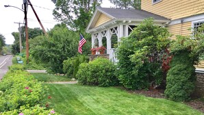 Ein gepflegter Rasen, eine Veranda mit weißer Geländer und eine Fahnenstange mit der US-amerikanischen Flagge.