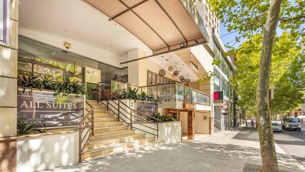 Ein Hotel Eingang mit einer Treppe, Glastüren und einem Schild mit der Aufschrift 'ALL SUITES'.