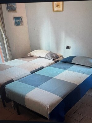 A single bed with a blue and white checkered bedspread, a wooden headboard, and a small bedside table.