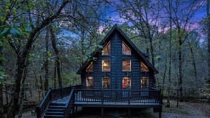 A cabin with a wooden exterior, a porch, and a staircase leading to the entrance. - Creekside Serenade relax by the running creek (Broken Bow)