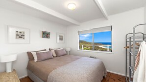 A bedroom with a bed, a window with a view of the sea, and a bunk bed with a towel. - 33 Degrees - Stunning Views by HolidayCo. (KILLCARE HEIGHTS)