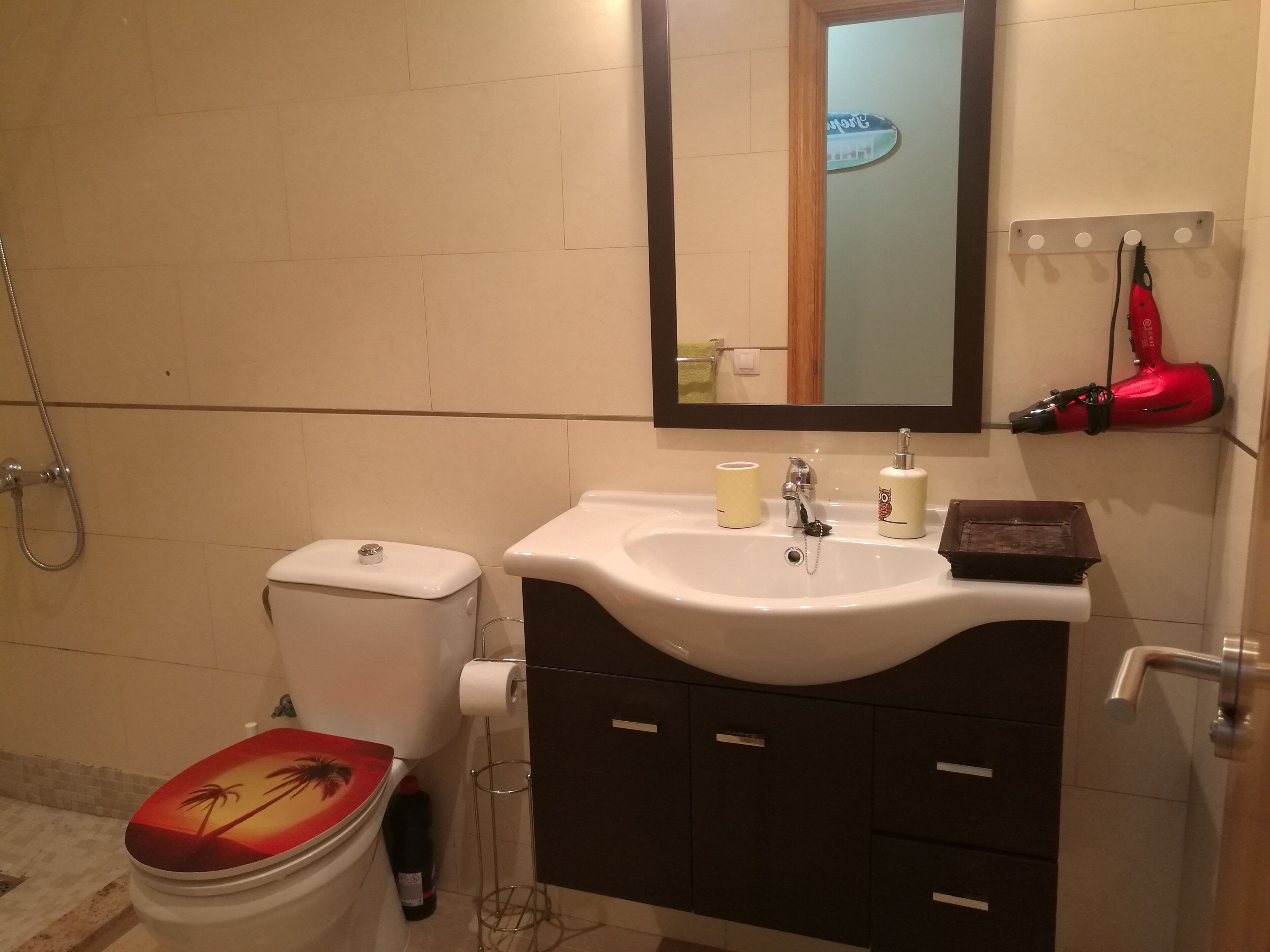 A bathroom with a toilet, sink, and mirror.