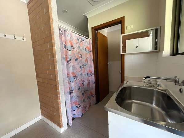 A bathroom with a shower curtain, a sink, and a mirror.