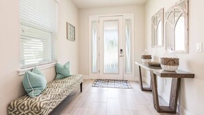 A hallway with a bench, a console table with baskets, and a door with frosted glass panels.