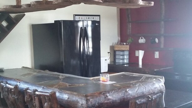 Eine Küche mit einer Kochinsel, Holzkästen, einem schwarzen Kühlschrank und einer roten Wand.