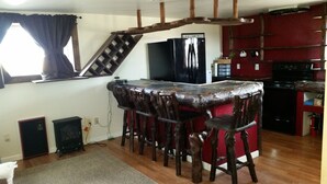 Eine Küche mit Bar, Holzhöhlen, einem Kühlschrank und einem Herd.