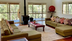 Un salón amplio con chimenea, ventanas grandes y ventilador de techo.