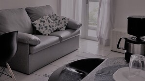 Un salon moderne avec un canapé gris, une table basse, une table à manger avec un plateau en verre et un ventilateur de plafond.