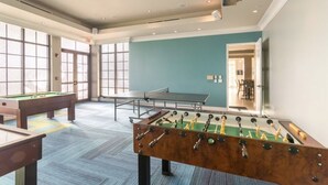 A recreational room with a foosball table, pool table, and ping pong table.