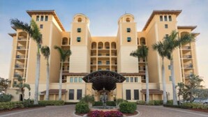 A multi-story hotel with a symmetrical facade, central entrance, and palm trees.