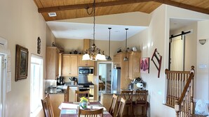 A spacious kitchen with wooden cabinets, a dining area with a table and chairs, and a staircase leading to another level.