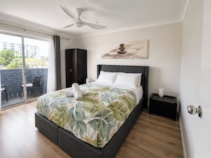 A modern bedroom with a bed, a ceiling fan, a view through a sliding door, and a painting on the wall. - West Beach Lagoon 123 - Location &amp; Views!!! (Scarborough)