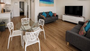 A modern living room with a glass dining table, white chairs, a grey sofa, and a flat-screen TV. - West Beach Lagoon 123 - Location &amp; Views!!! (Scarborough)