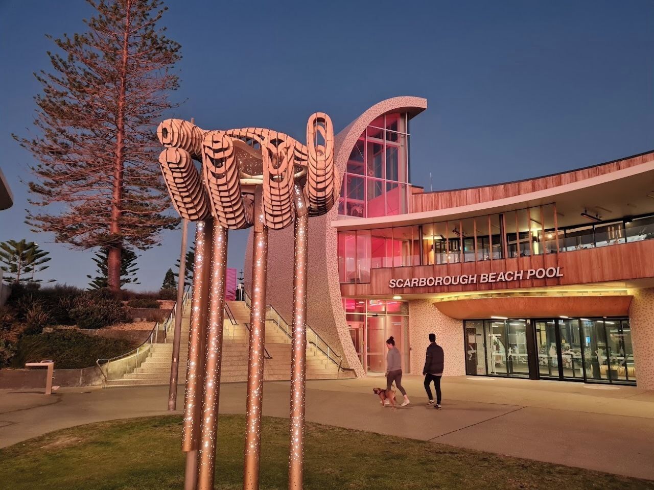 A modern building with a curved facade and a sign reading 'Scarborough Beach Pool'.