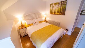 A bedroom with a bed, bedside lamps, a painting, and a radiator.