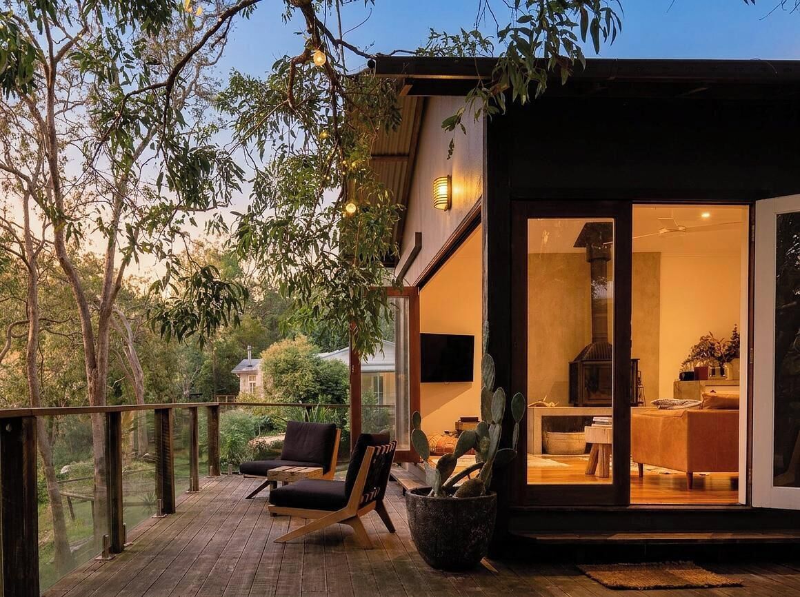 A modern house with a deck, a cactus plant, and a television in the living room.