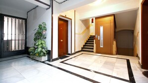 A hallway with a tiled floor, a potted plant, and a staircase leading to another room. - Charming Malasaña (Madrid)