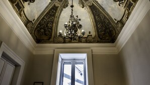 Un sostre ornamentat amb un penjador de llum, una porta i una paret amb dibuixos.