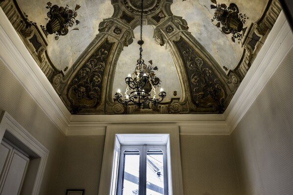 An ornate ceiling with a chandelier, a doorway, and a patterned wall. - Apartment at the San Carlo Theater (Napoli)