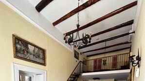 Una habitació àmplia amb un sòl de fusta en relleu, una escala que condueix a un nivell superior i un penjall.