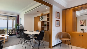 Un espace repas moderne avec une table ronde, des chaises noires et un meuble en bois doté d’étagères.