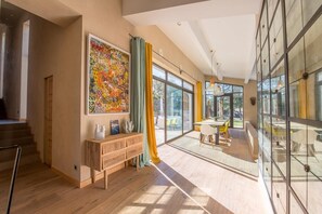 A spacious room with a large window, a wooden bench, and a colorful abstract painting.