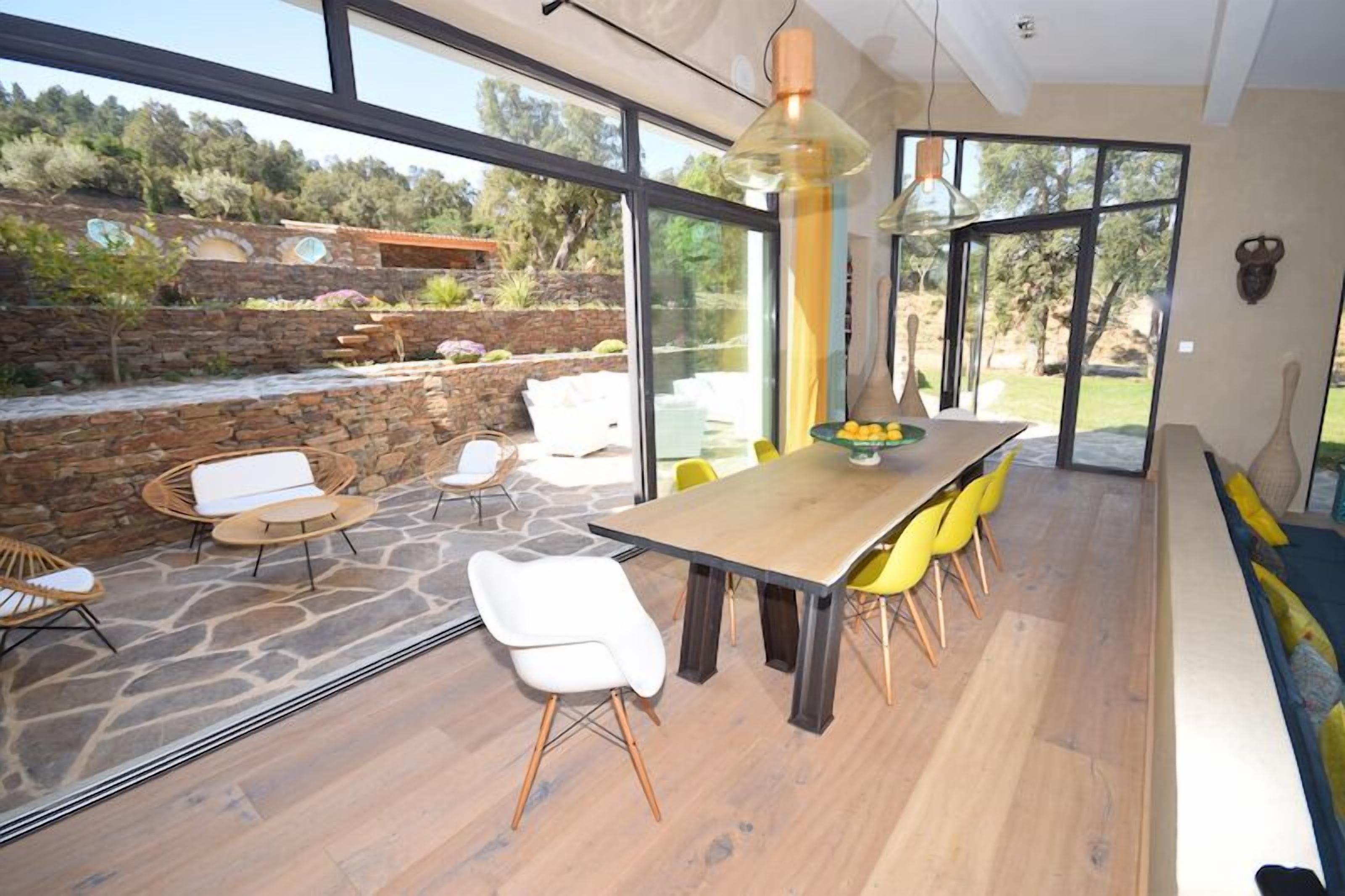 Un espace de restauration moderne avec une longue table, des chaises jaunes et un mur en pierre en arrière-plan.