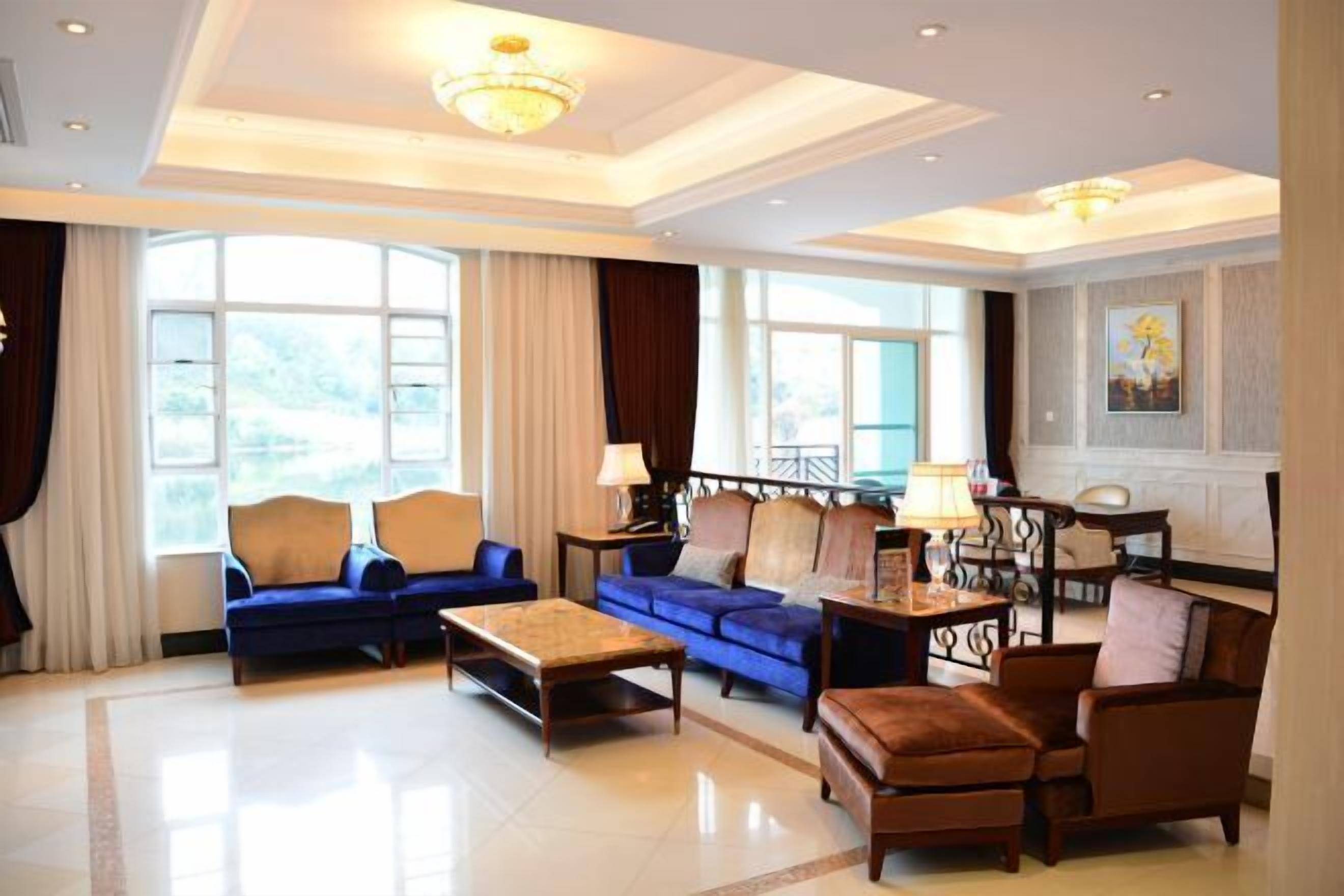 A spacious living room with a chandelier, blue sofas, a coffee table, and a brown armchair.