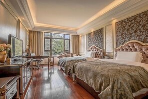 A spacious bedroom with two beds, a desk, and a chair.