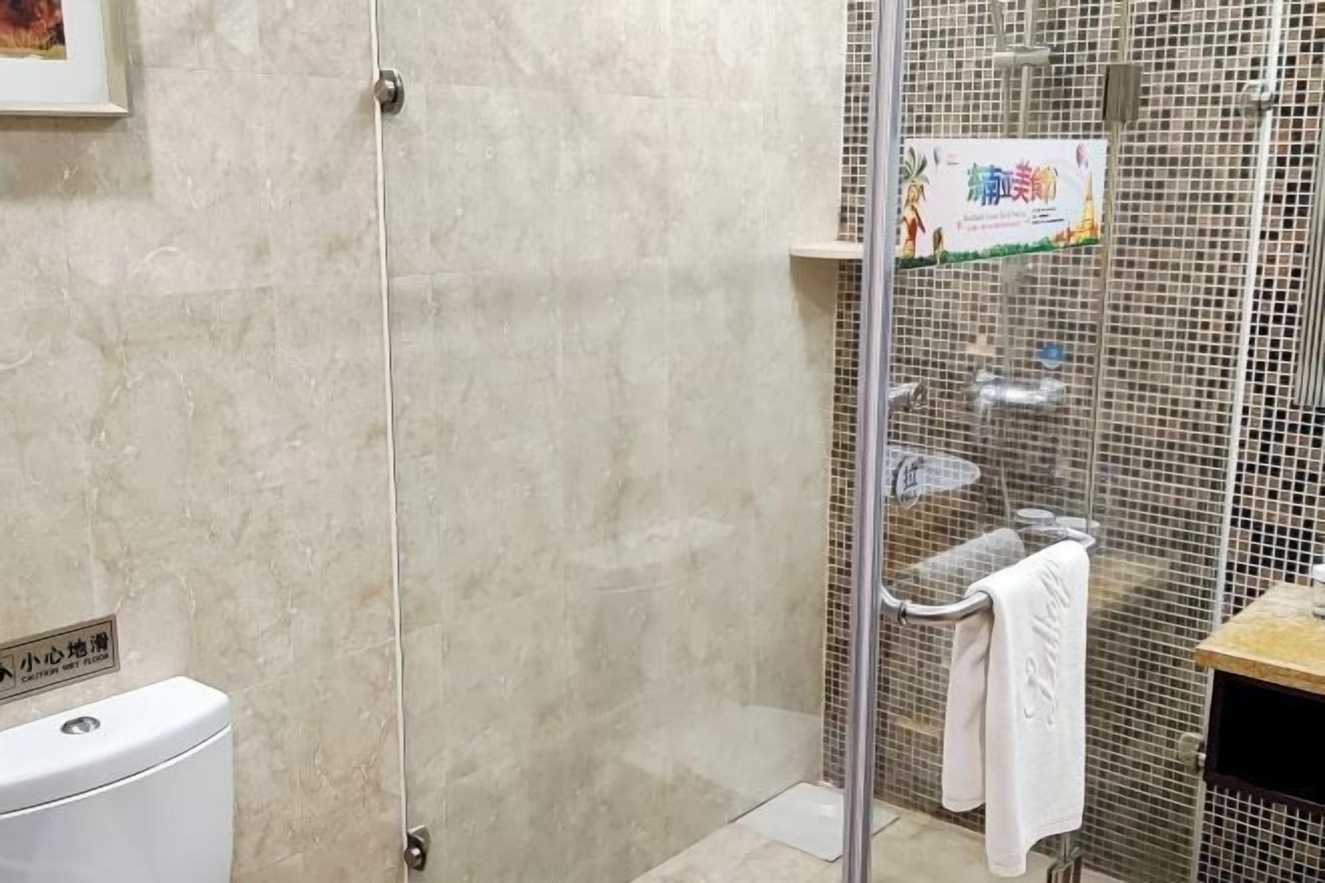 A bathroom with a glass shower enclosure, a toilet, and a towel rack.