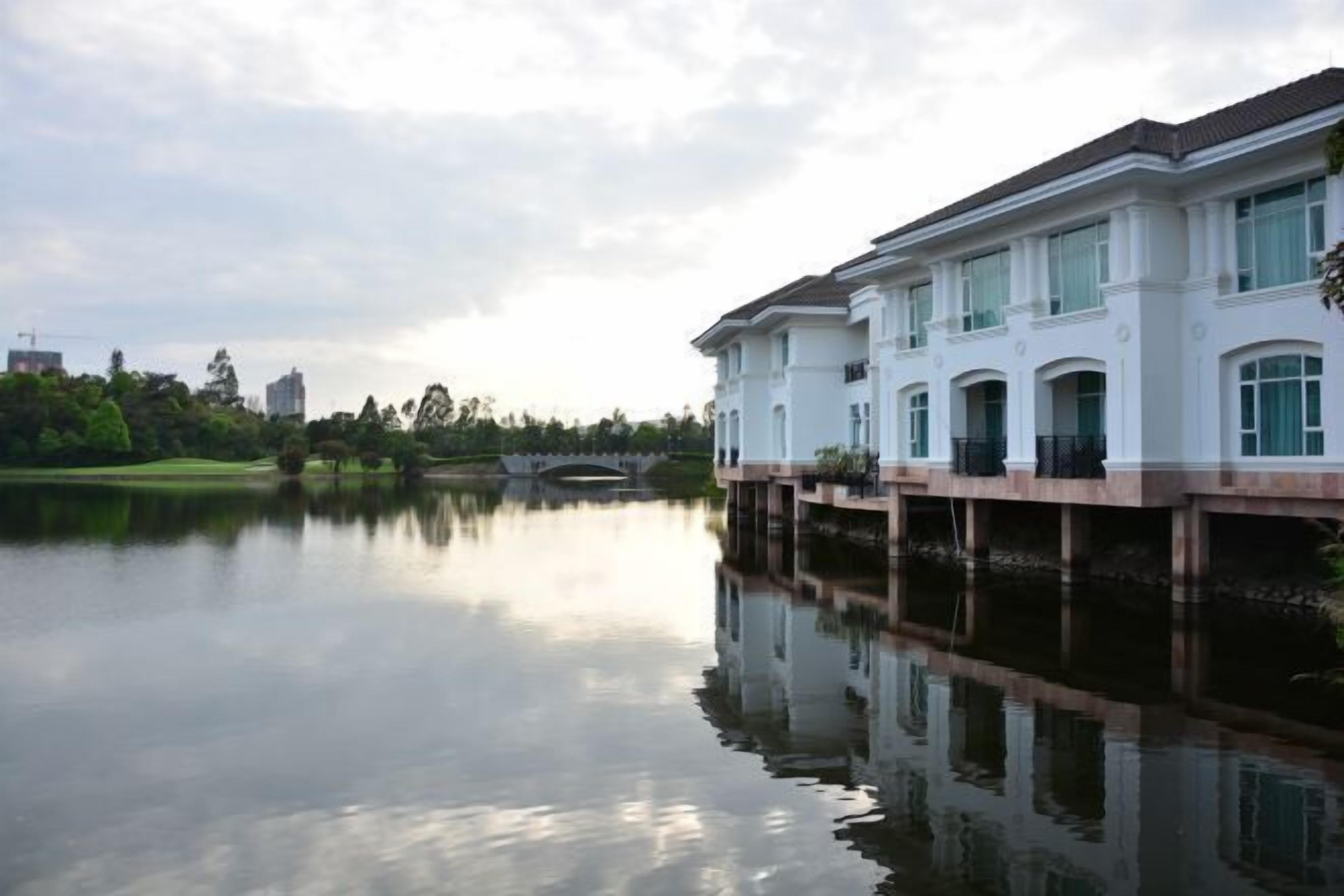 A waterfront property with a white building featuring multiple balconies and a reflection in the water.