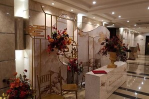 A reception area with a marble counter, chairs, and floral arrangements.