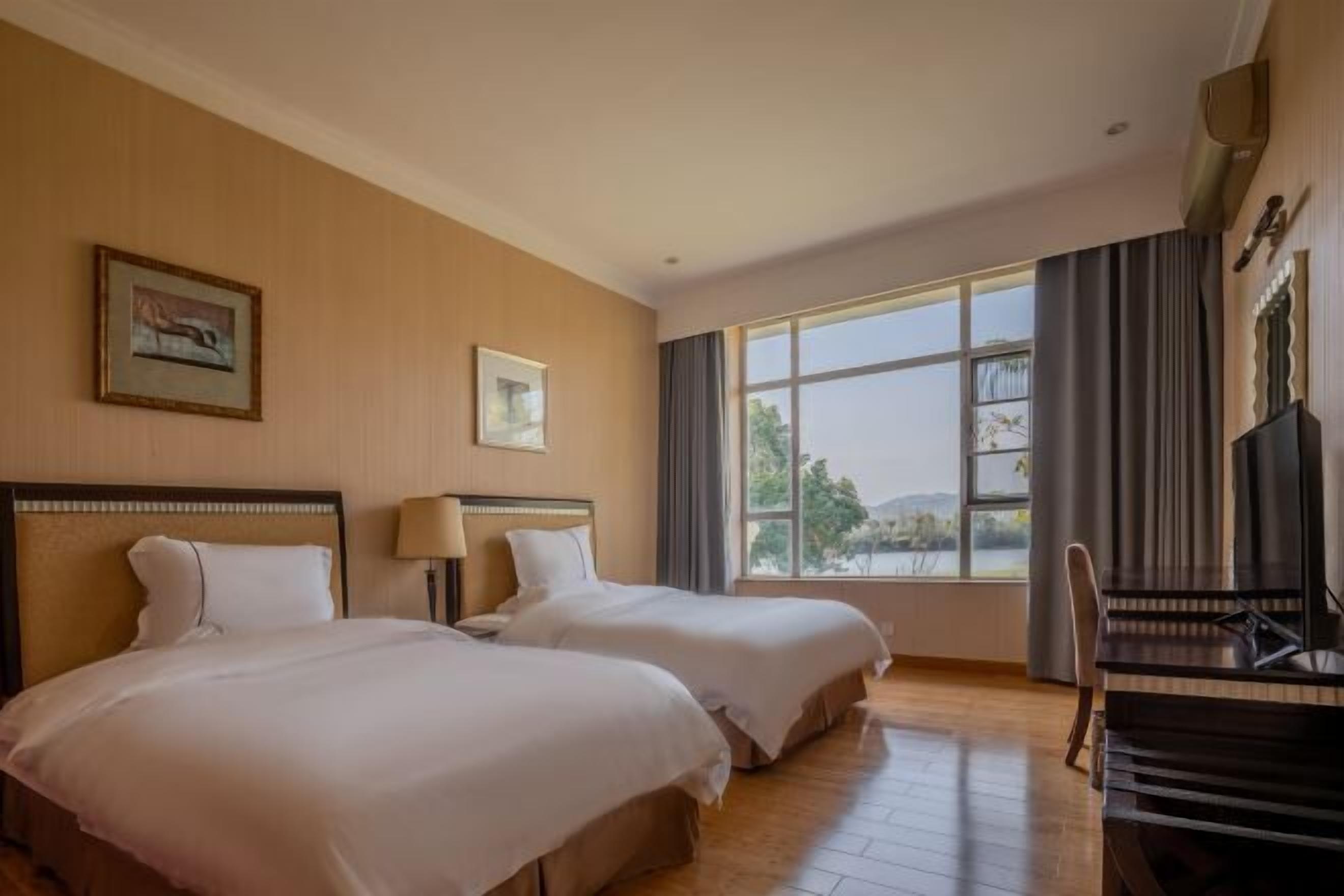 Una habitación de hotel con dos camas, un piano y un gran ventanal con vistas.
