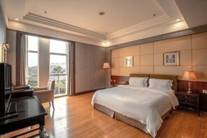 A hotel room with a large bed, a desk, and a view of the outdoors.