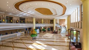 A spacious lobby with a high ceiling, multiple floors, and a central staircase.