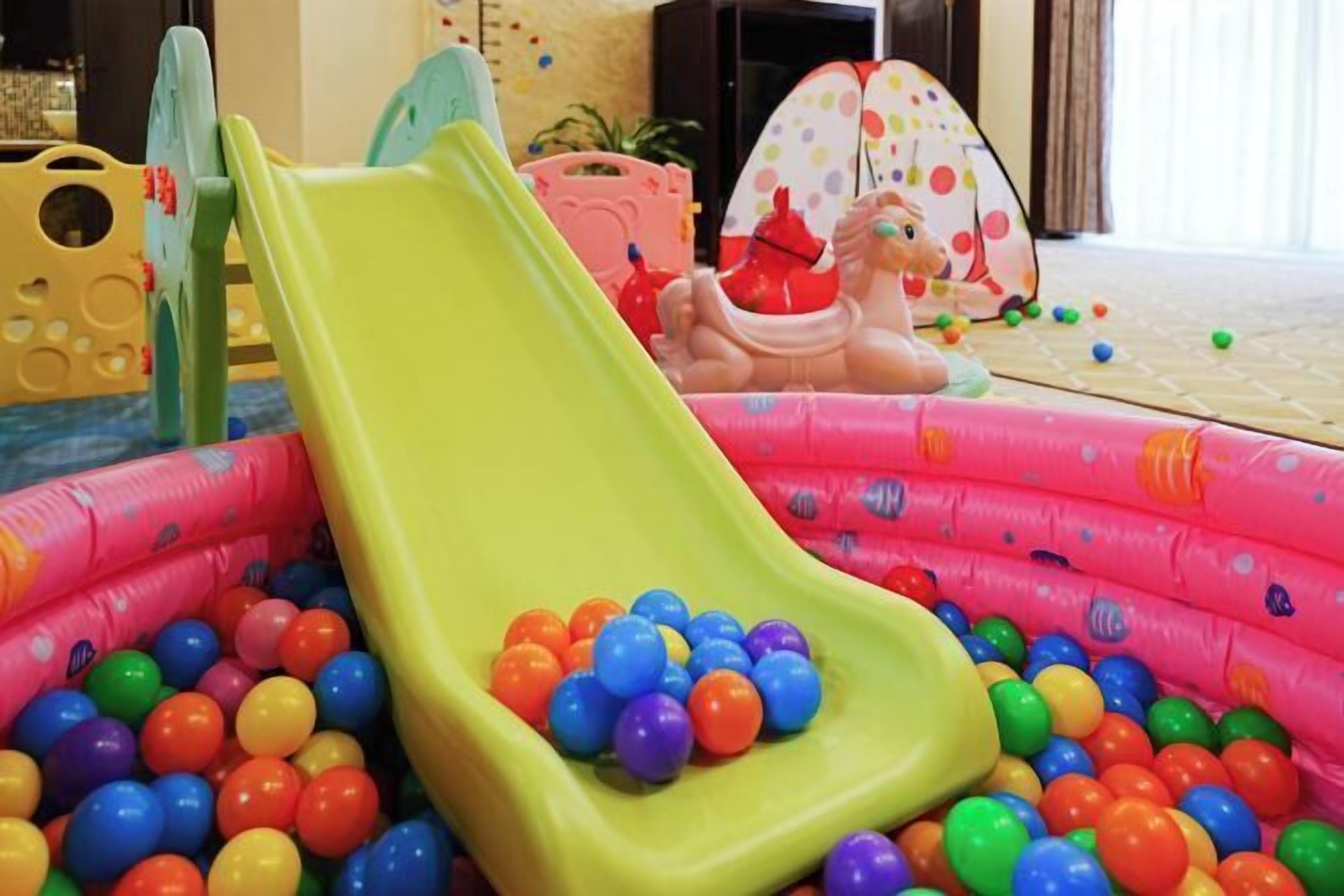An inflatable pool with a slide and colorful plastic balls.