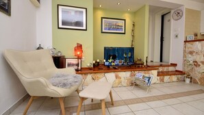 A living room with a sofa, a small table, a TV, and a stone wall. - Cosy apartment for 2 guests with WIFI, pool, A/C, TV, terrace and pets allowed (Solin)