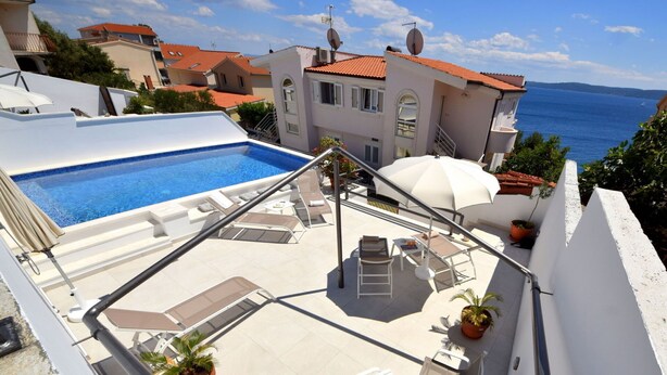 A rooftop pool area with lounge chairs, a table with fruit, and a view of the sea. - Cosy apartment for 2 guests with WIFI, pool, A/C, TV, terrace and pets allowed (Solin)