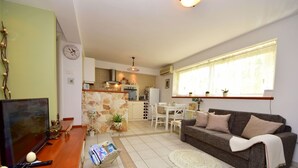 A compact living space with a kitchenette, a dining area, and a seating area with a sofa and a TV. - Cosy apartment for 2 guests with WIFI, pool, A/C, TV, terrace and pets allowed (Solin)