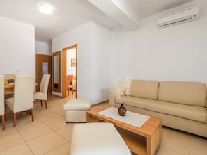 A modern living room with a sofa, a coffee table, and a dining area with chairs and a table.