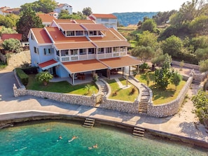 A multi-story house with a swimming pool, stone walls, and a garden.