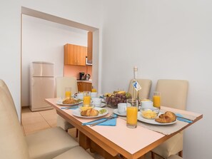 Una mesa con sillas, un refrigerador, un microondas y una cocina.