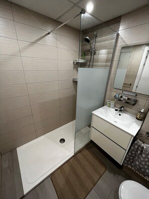 Un baño moderno con ducha, lavabo e inodoro.
