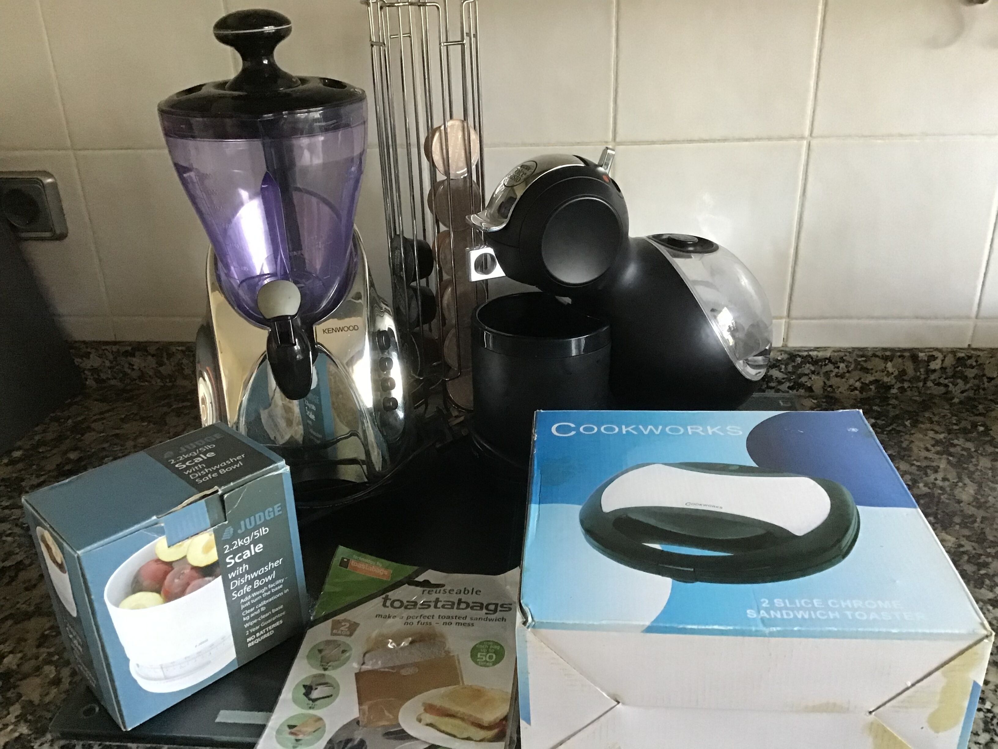 Une cuisine équipée d’un mixeur Kenwood, d’une machine à café noire, d’un appareil à toasts Cookworks et d’une balance JUGGE.