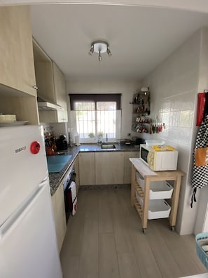 A compact kitchen with a refrigerator, microwave, sink, and a small table.