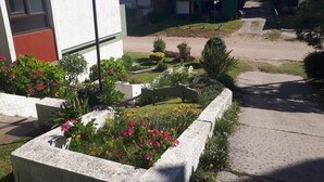 Un pati amb llits de flors, un fanal i un edifici amb un rètol que diu "VENDES".
