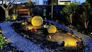 Ein angelegter Garten mit dekorativen Kugeln, einer Bank und einer Steinsäule.